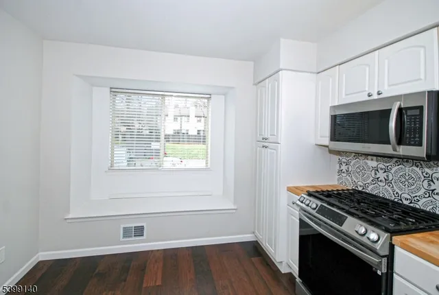 a kitchen with granite countertop a stove a sink and a microwave