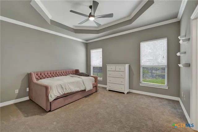 a spacious bedroom with a bed a dresser and a chandelier