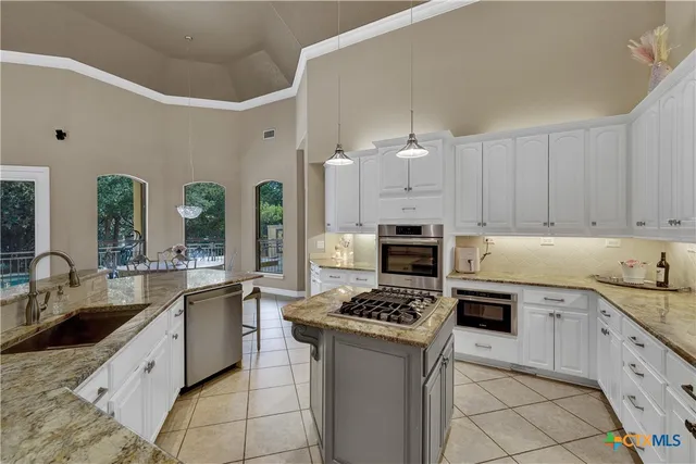 a kitchen with granite countertop a sink a stove cabinets and counter space