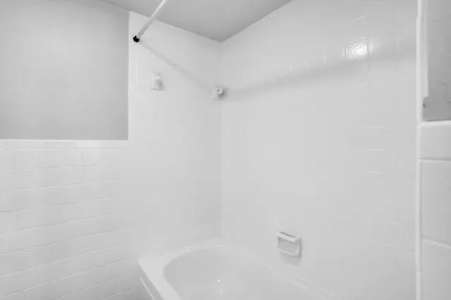 an empty room with a chandelier fan and windows