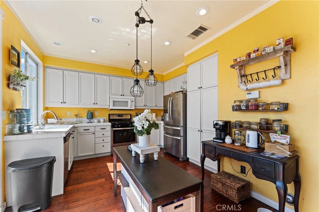 5922 Abernathy Drive Riverside, CA 92507 - Photo 11 of 29 a kitchen with a refrigerator a stove and a dining table with wooden floor