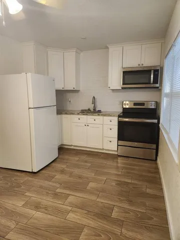 a kitchen with granite countertop a refrigerator stove a sink and dishwasher with wooden floor