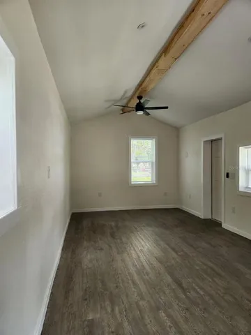 an empty room with wooden floor cabinet and windows