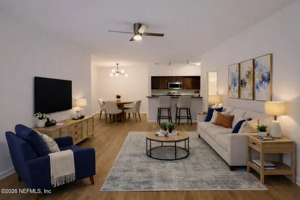 a living room with furniture a flat screen tv and kitchen view