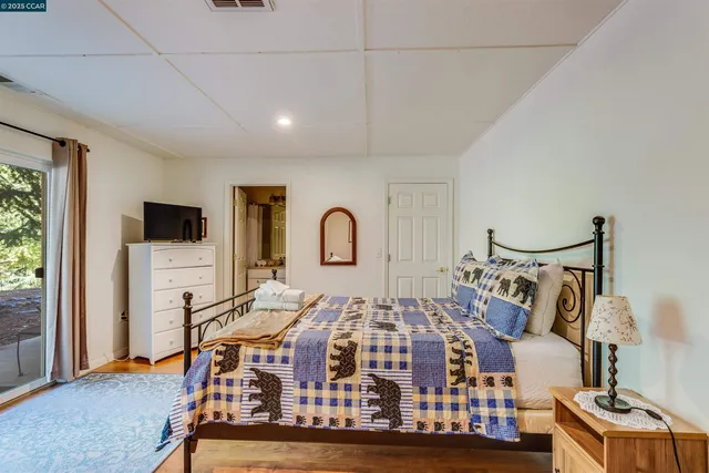 a bedroom with a bed a flat tv screen and a dresser