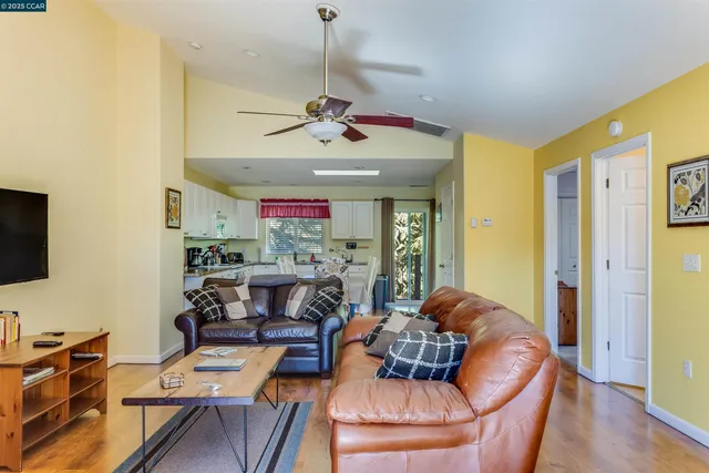 a kitchen with stainless steel appliances kitchen island granite countertop a stove a sink a refrigerator and white cabinets with wooden floor