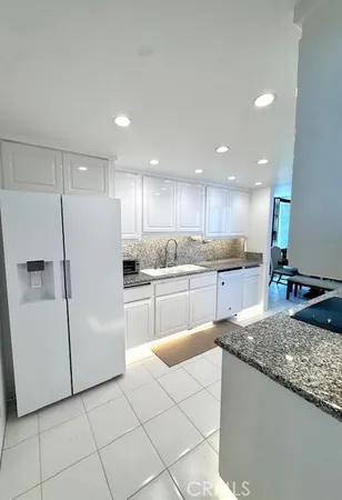 a kitchen with kitchen island granite countertop white cabinets and refrigerator