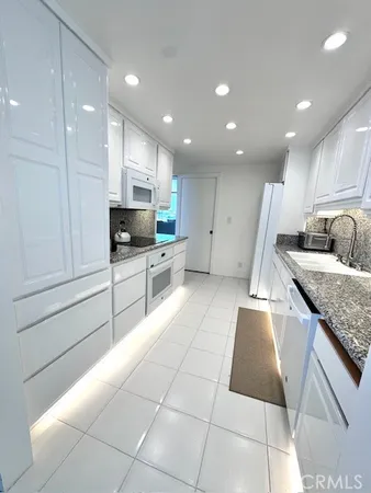 a large kitchen with stainless steel appliances granite countertop a large counter top and a stove top oven with wooden floor