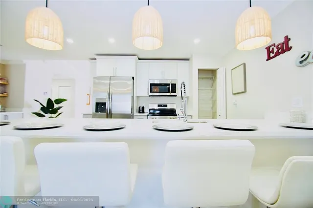 a kitchen with stainless steel appliances kitchen island granite countertop a sink and a refrigerator