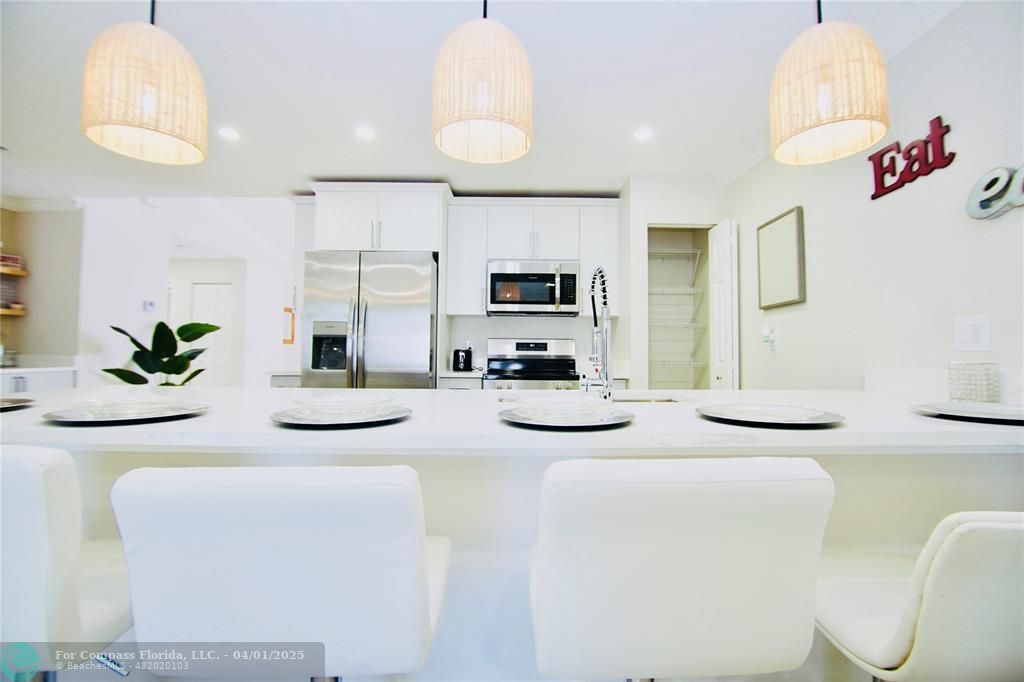 a kitchen with stainless steel appliances kitchen island granite countertop a sink and a refrigerator