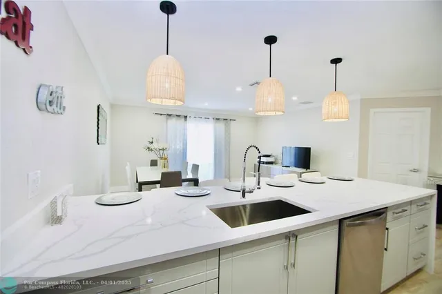 a kitchen with a sink a chandelier and living room view