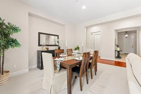 a kitchen with stainless steel appliances granite countertop wooden cabinets a sink a stove a dining table and chairs