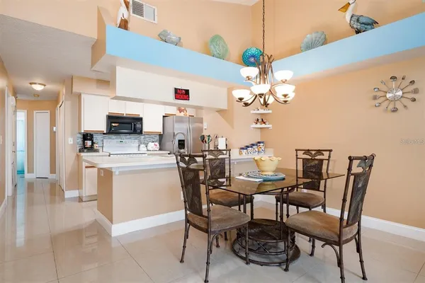 a dining room filled chandelier and kitchen view