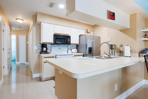a kitchen with stainless steel appliances a sink a refrigerator a microwave a sink and cabinets