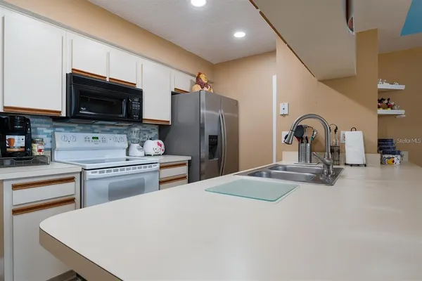 a kitchen with stainless steel appliances granite countertop a refrigerator a stove a sink and a microwave