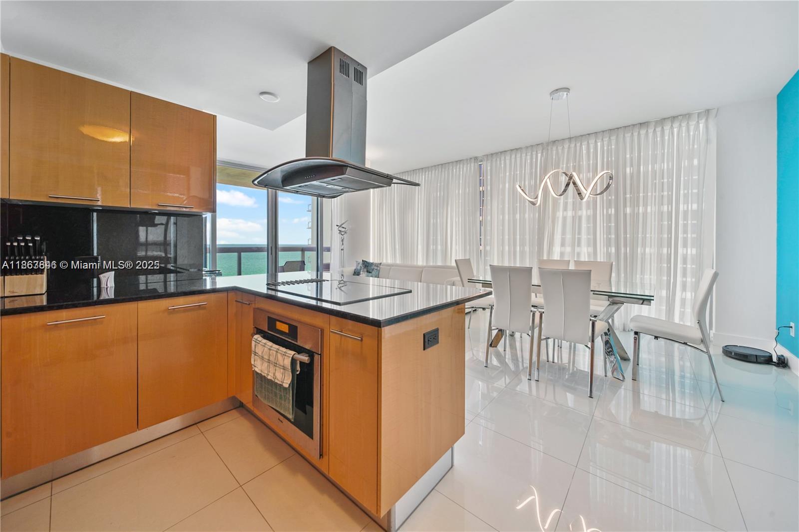 6899 Collins Avenue, Unit 808 Miami Beach, FL 33141 - Photo 15 of 31 a kitchen with stainless steel appliances granite countertop a table chairs and a sink