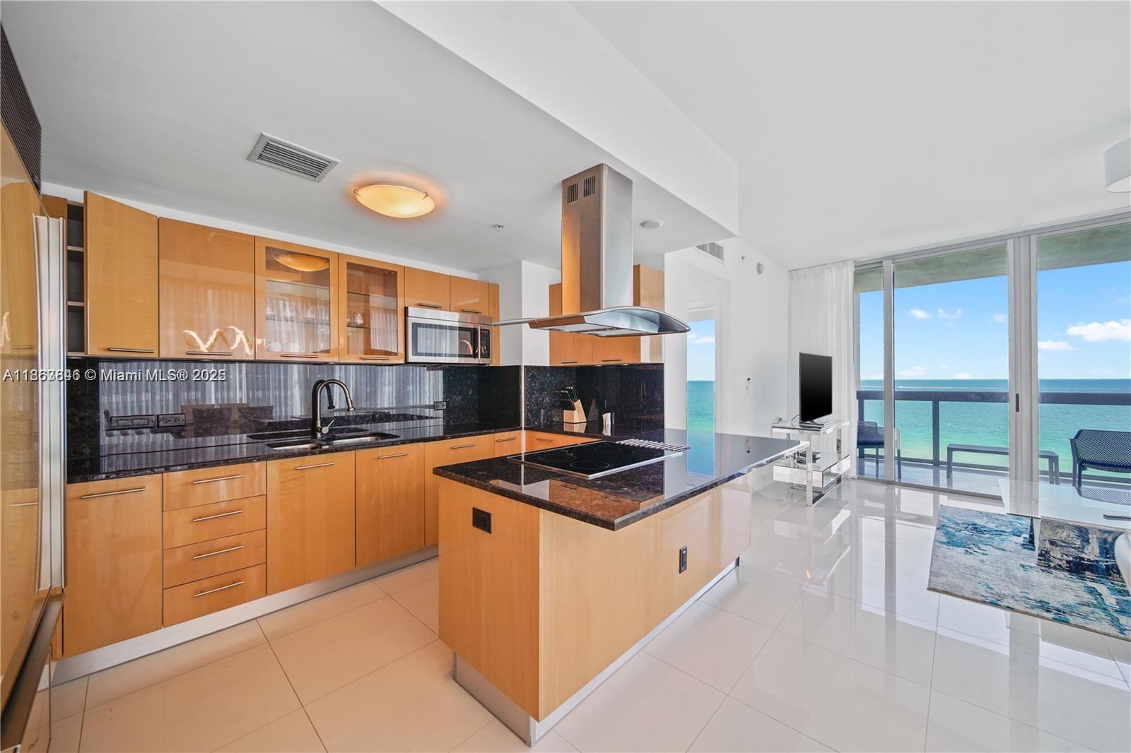 6899 Collins Avenue, Unit 808 Miami Beach, FL 33141 - Photo 16 of 31 a kitchen with stainless steel appliances a sink a stove and a view of living room