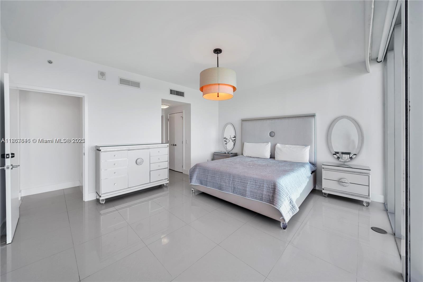 6899 Collins Avenue, Unit 808 Miami Beach, FL 33141 - Photo 21 of 31 a bedroom with a bed and a chandelier