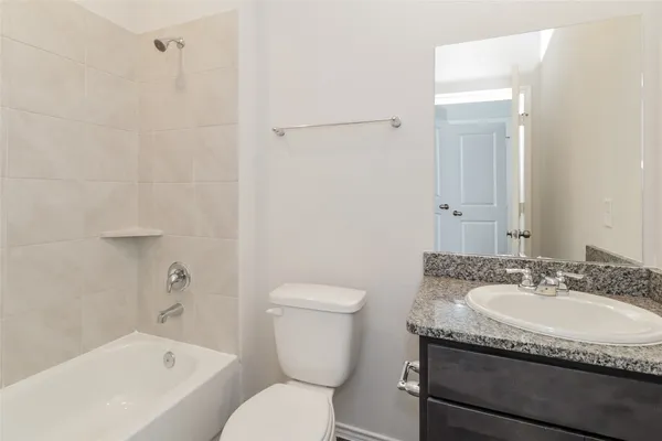 a bathroom with a granite countertop sink a toilet and bathtub