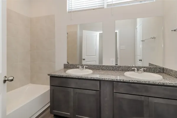 a bathroom with a granite countertop sink a mirror and a bathtub