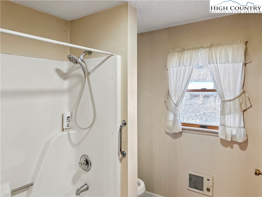 2496 Tucker Road Lansing, NC 28643 - Photo 14 of 20 a bathroom with a window shower and a sink