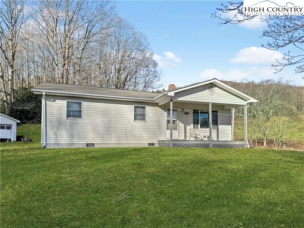 2496 Tucker Road Lansing, NC 28643 - Photo 3 of 20 a front view of a house with a garden and trees