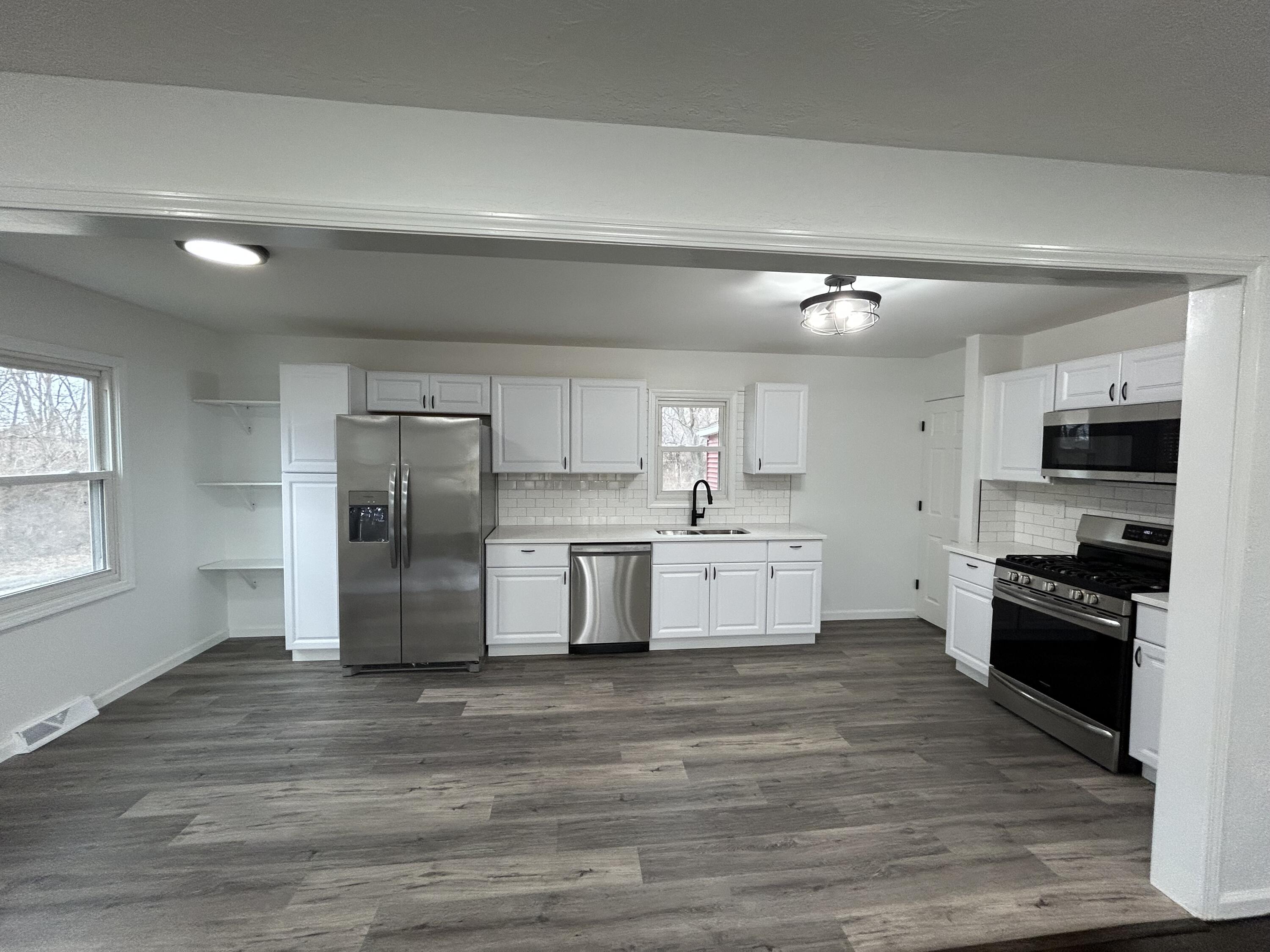 6701 Madison Street Merrillville, IN 46410 - Photo 2 of 25 a large kitchen with stainless steel appliances granite countertop a stove a sink dishwasher a refrigerator and white cabinets with wooden floor