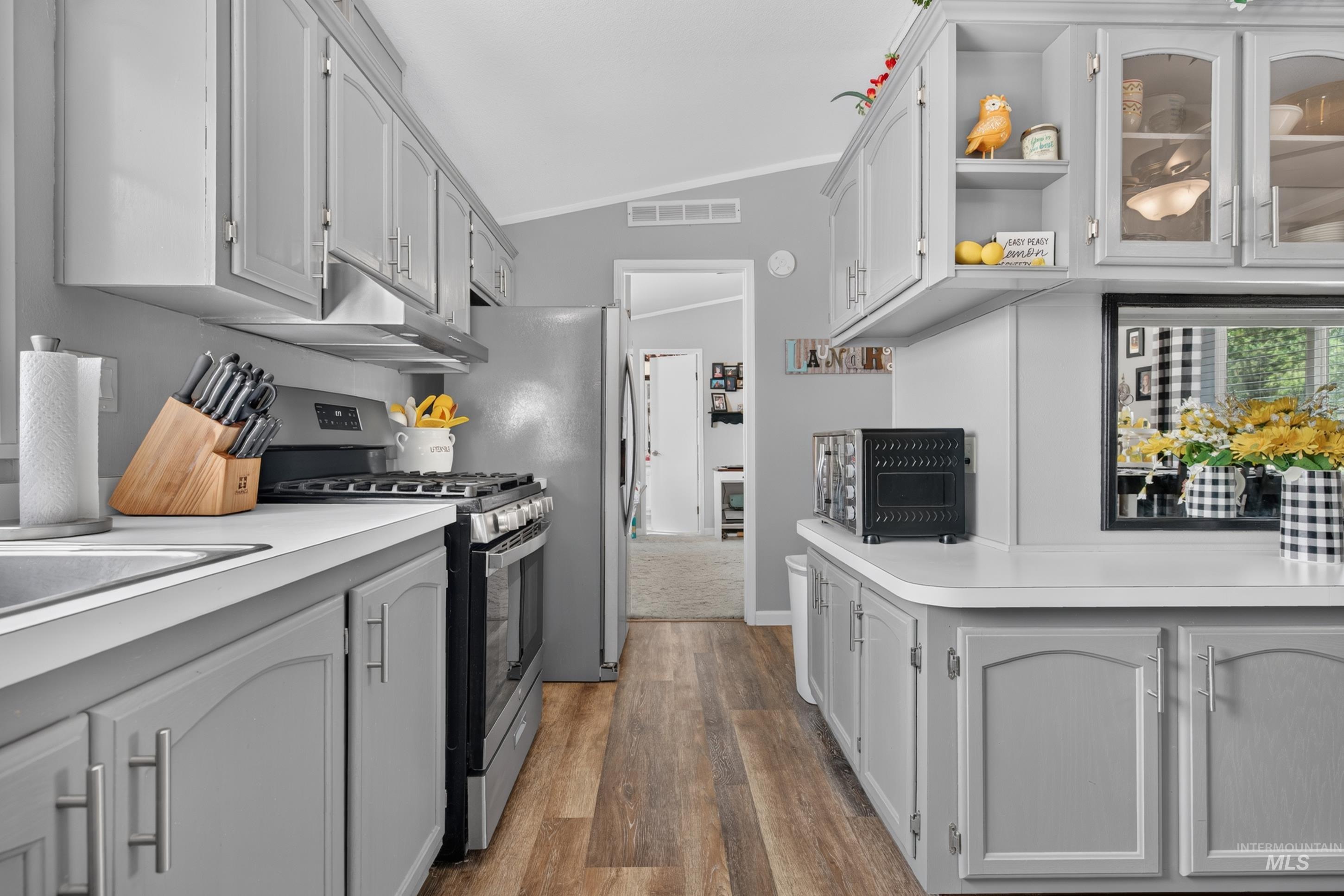 7417 Map Rock Road Caldwell, ID 83607 - Photo 18 of 32 Kitchen featuring wood-finish flooring, light-toned cabinetry with metal hardware, a stainless steel range, and a stainless steel refrigerator