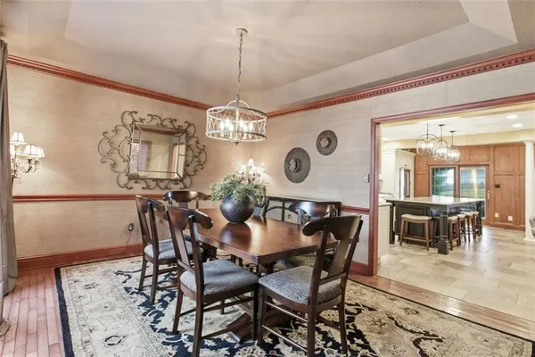 a view of a dining room and livingroom with furniture a chandelier fan and wooden floor