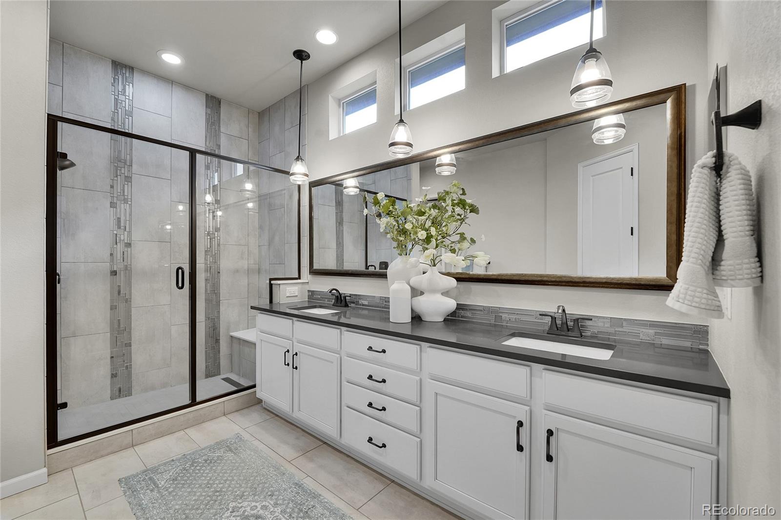 3429 Goodyear Street Castle Rock, CO 80109 - Photo 13 of 32 a bathroom with a double vanity sink mirror and shower