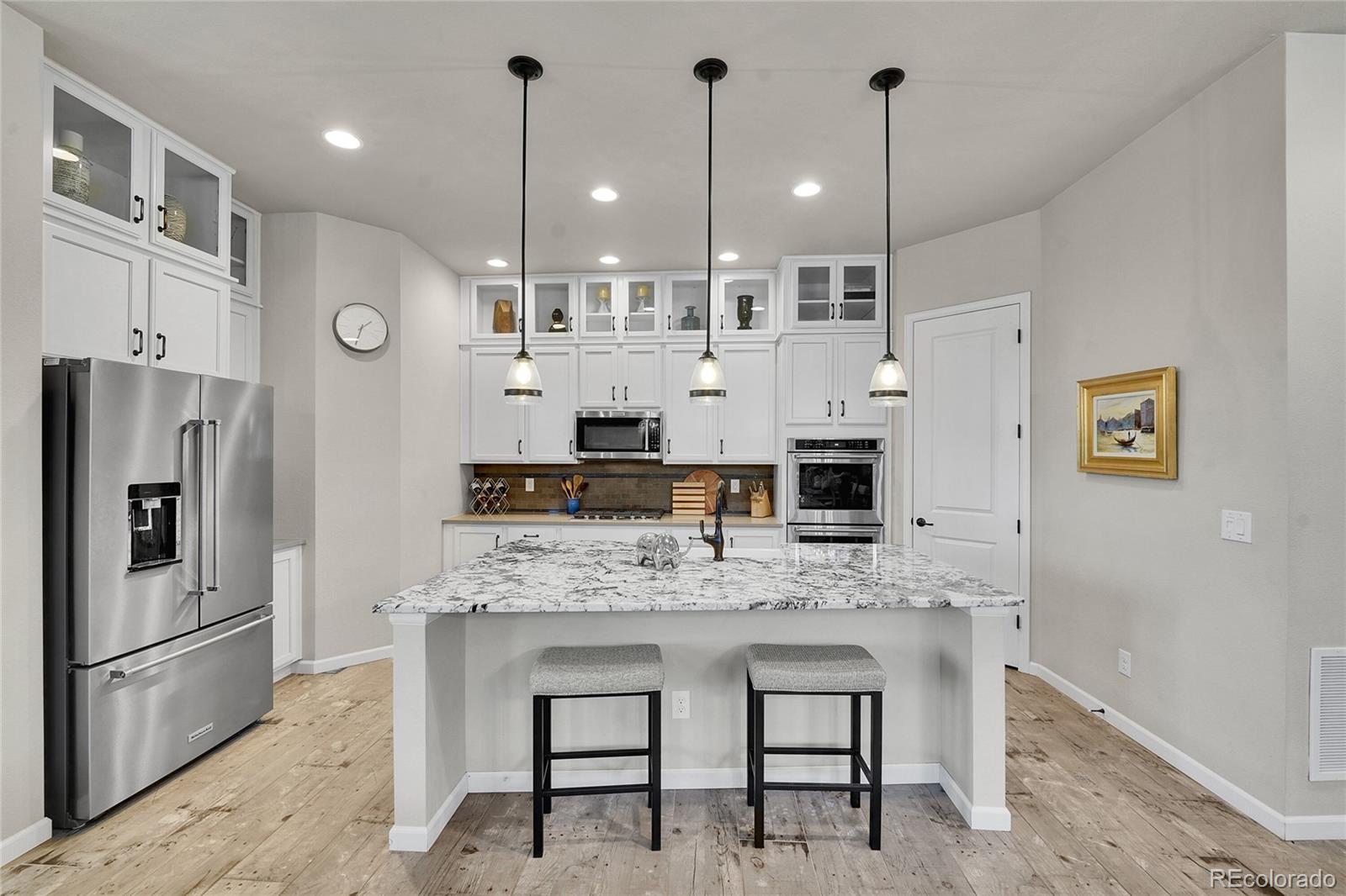 3429 Goodyear Street Castle Rock, CO 80109 - Photo 7 of 32 a large kitchen with stainless steel appliances kitchen island granite countertop a table chairs stove and refrigerator