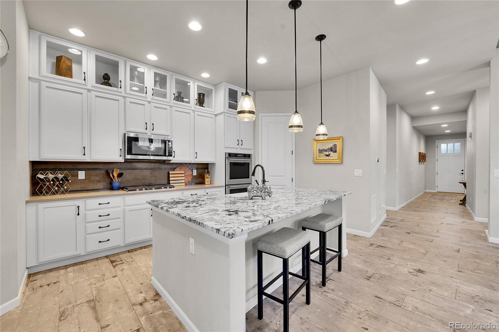 3429 Goodyear Street Castle Rock, CO 80109 - Photo 8 of 32 a large kitchen with stainless steel appliances kitchen island granite countertop a stove a sink a refrigerator and a granite counter tops