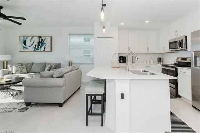 a living room with stainless steel appliances kitchen island a table and chairs