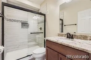a bathroom with a granite countertop sink a toilet and shower