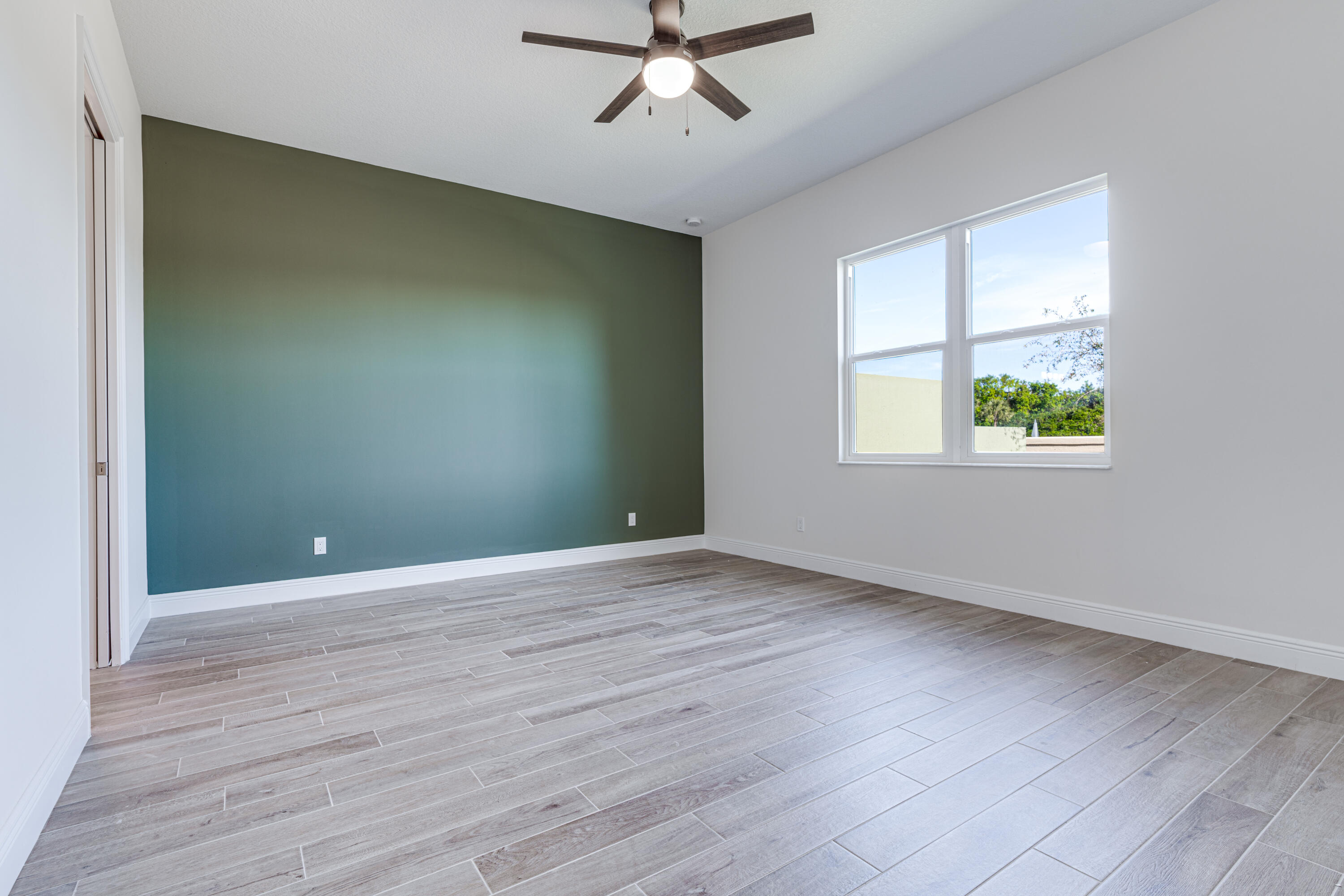 2005 Bridgepointe Circle, Unit 98 Vero Beach, FL 32967 - Photo 11 of 31 an empty room with wooden floor chandelier fan and windows