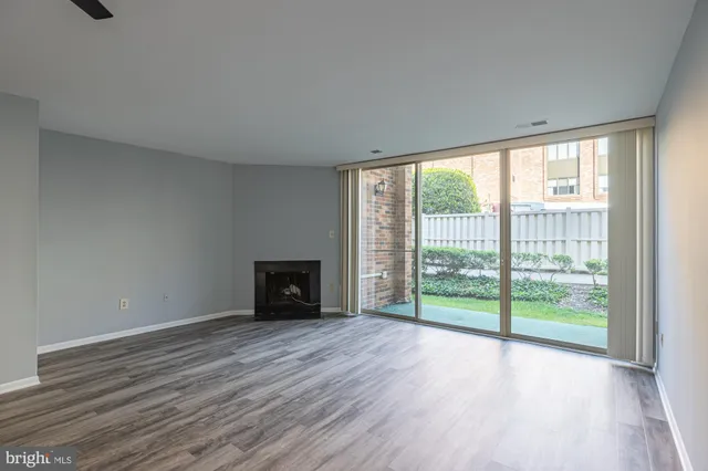 a view of an empty room with wooden floor and a fireplace