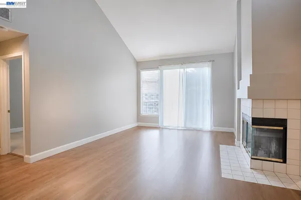 an empty room with wooden floor fireplace and windows