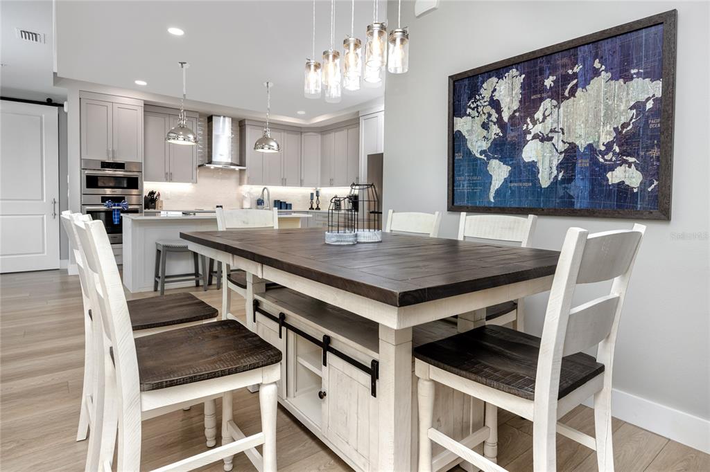 300 150th Avenue, Unit 502 Madeira Beach, FL 33708 - Photo 16 of 52 a kitchen with stainless steel appliances kitchen island a table chairs in it and wooden floors