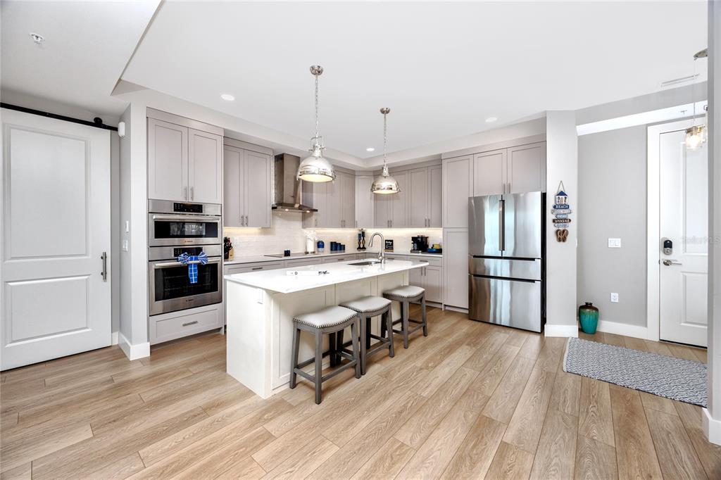 300 150th Avenue, Unit 502 Madeira Beach, FL 33708 - Photo 4 of 52 a large kitchen with stainless steel appliances a stove center island wooden floor and cabinets
