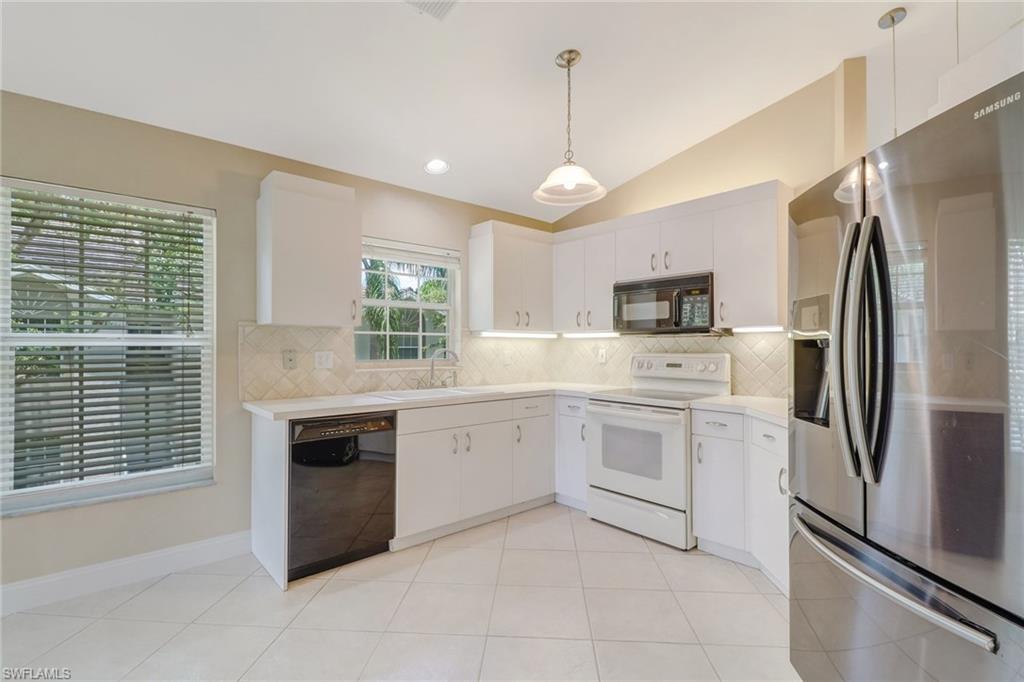 3765 Fieldstone Boulevard, Unit 1304 Naples, FL 34109 - Photo 11 of 33 a kitchen with white cabinets stainless steel appliances and a window