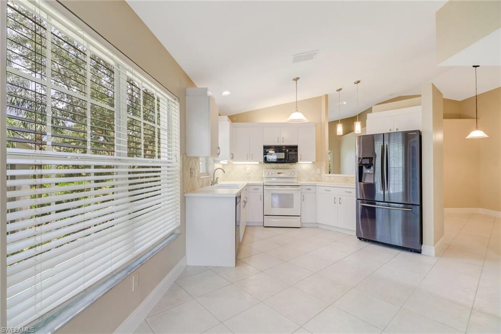 3765 Fieldstone Boulevard, Unit 1304 Naples, FL 34109 - Photo 12 of 33 a kitchen with white cabinets and stainless steel appliances