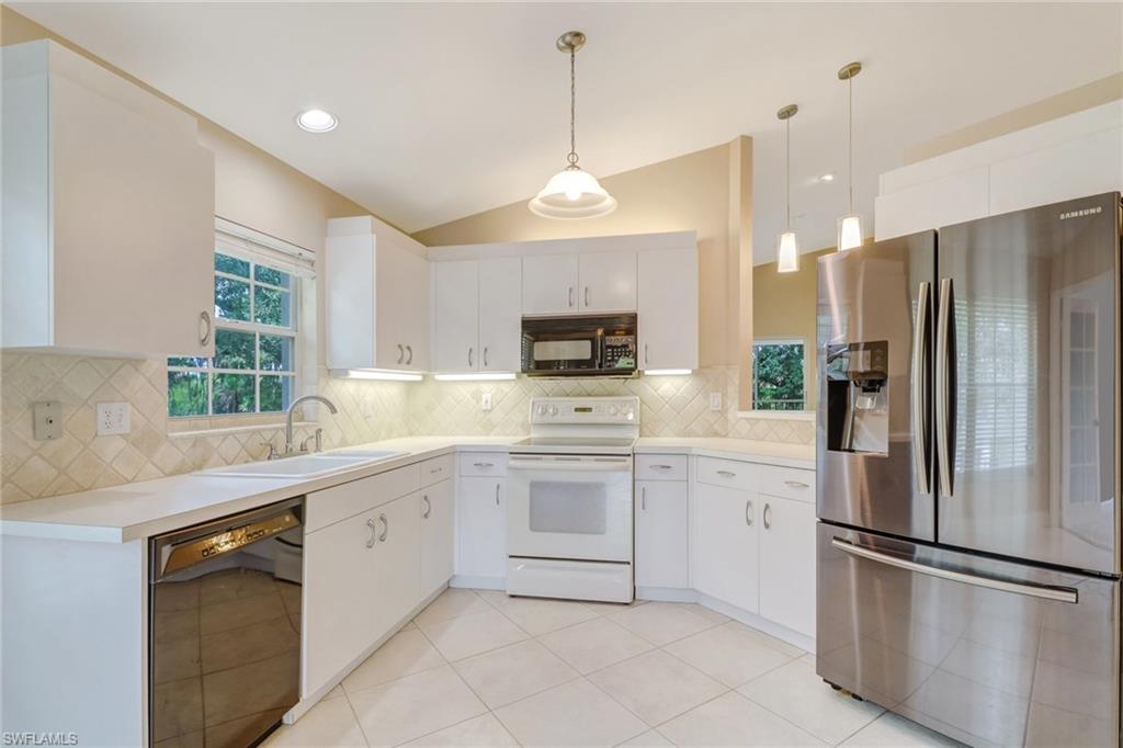 3765 Fieldstone Boulevard, Unit 1304 Naples, FL 34109 - Photo 9 of 33 a kitchen with white cabinets and stainless steel appliances