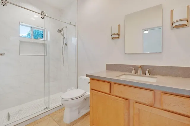 a bathroom with a granite countertop sink a toilet and a shower