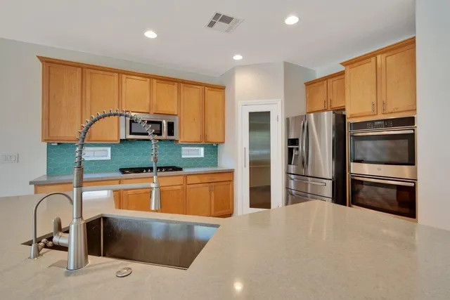 a kitchen with stainless steel appliances granite countertop a refrigerator and a stove top oven