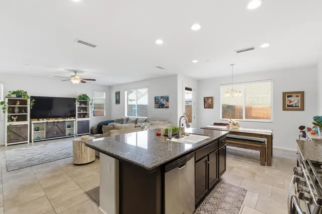 a kitchen island with granite countertop a sink and chairs