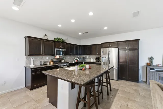 a kitchen with stainless steel appliances granite countertop a sink a stove a refrigerator and a refrigerator