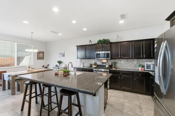a kitchen island with granite countertop a sink and chairs