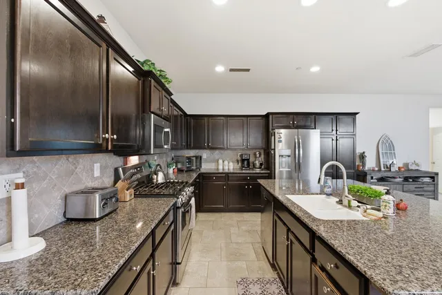 a kitchen with stainless steel appliances granite countertop a sink a stove and a wooden floors