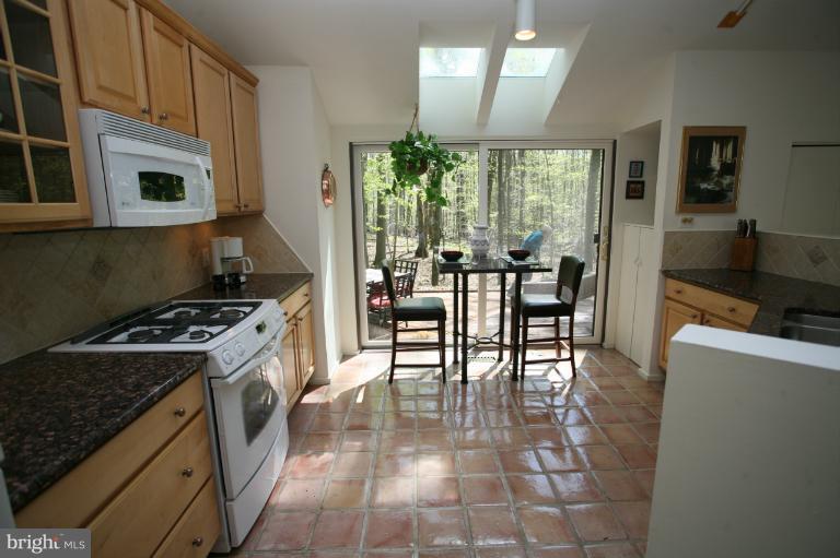 10927 Lawyers Road Reston, VA 20191 - Photo 23 of 30 a kitchen with stainless steel appliances granite countertop a stove top oven a sink a dining table and chairs with wooden floor
