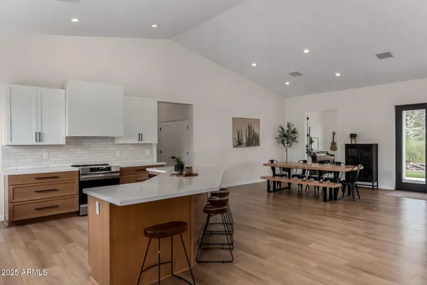 a kitchen with stainless steel appliances granite countertop a stove a refrigerator a dining table and chairs with wooden floor